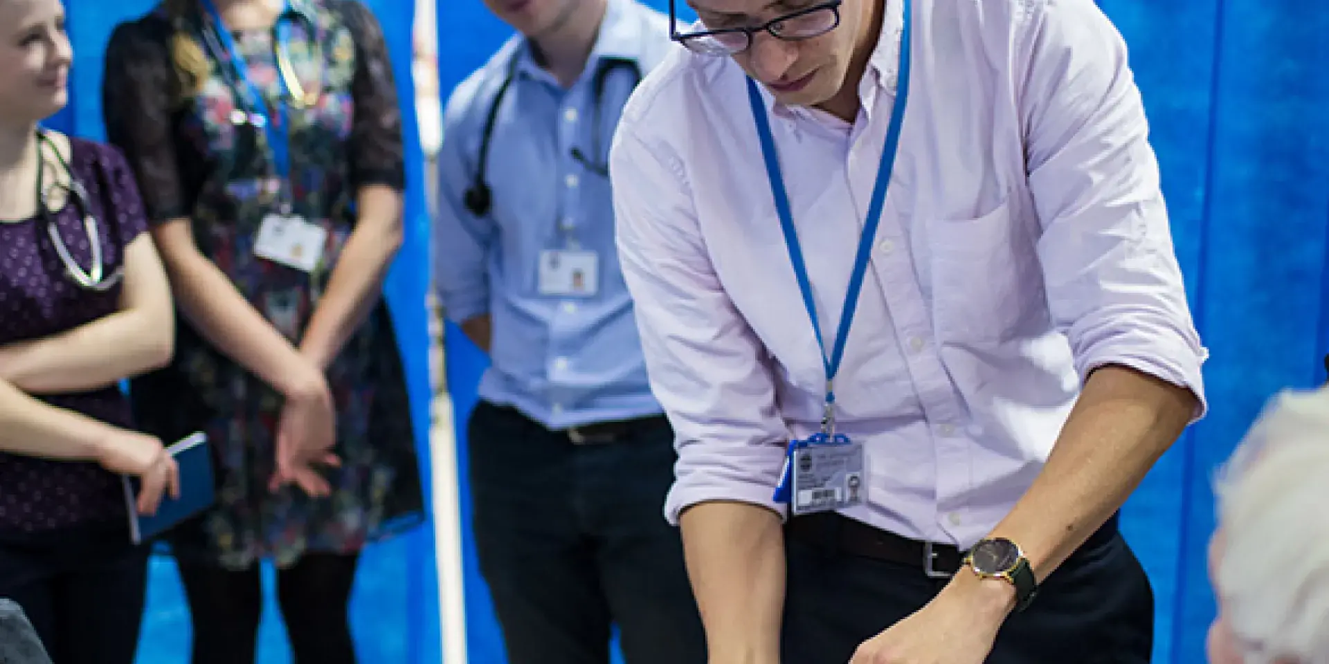 Medical students examine an elderly patient seen in profile