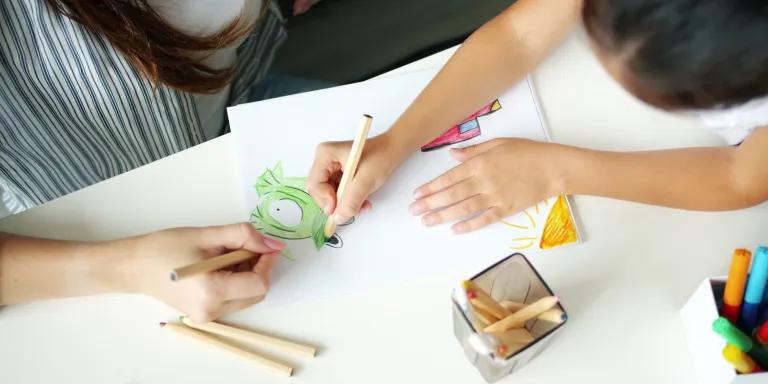 birdseye view of a child and therapist drawing pictures on some paper