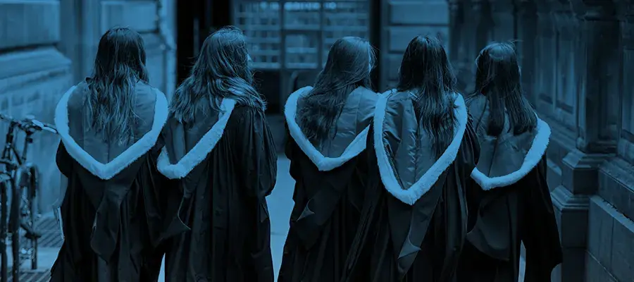 Group of 5 graduating students, walking away from camera in their graduation gowns