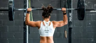 woman lifting wights overhead at the gym flaxing back muscles 