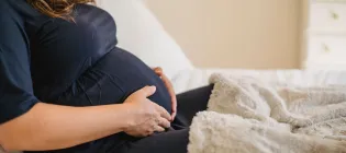 Prgnant woman sitting down holding her belly