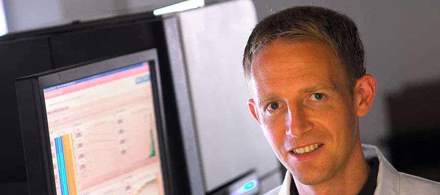 Dr Ross Houston beside a computer