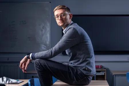 Callum Cruikshank sitting on a desk and turned to look at the camera