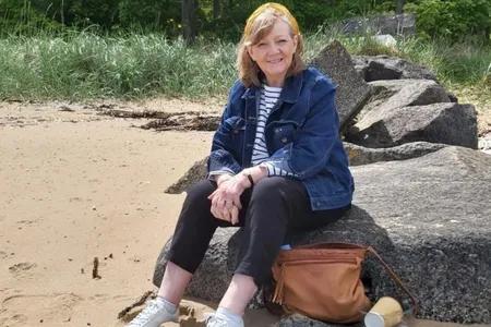 Mid shot of Faye sitting on a beach