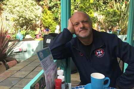 Mid shot of Derek sitting at a cafe table outdoors