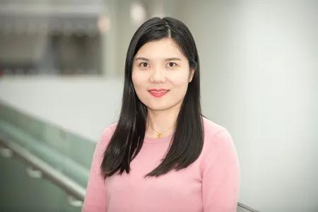 Xue Li, smiling and wearing a pink sweater