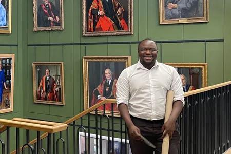 Head shot of Abduljabar Hamza standing on staircase with paintings in background