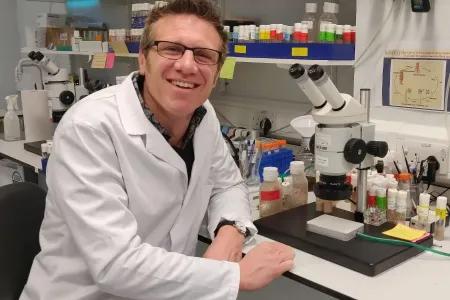 Portait of Will, wearing a lab coat, with lab in background