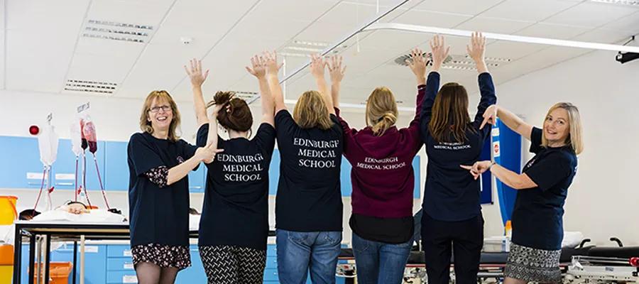Group shot of the team in the Clinical Skills Centre, with most of the team facing away from the camera