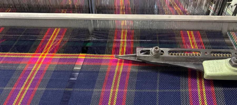 Image of tartan being produced in the mill will a tool on the material