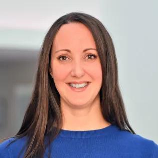 portait of woman smiling with long brown hair wearing a blue top