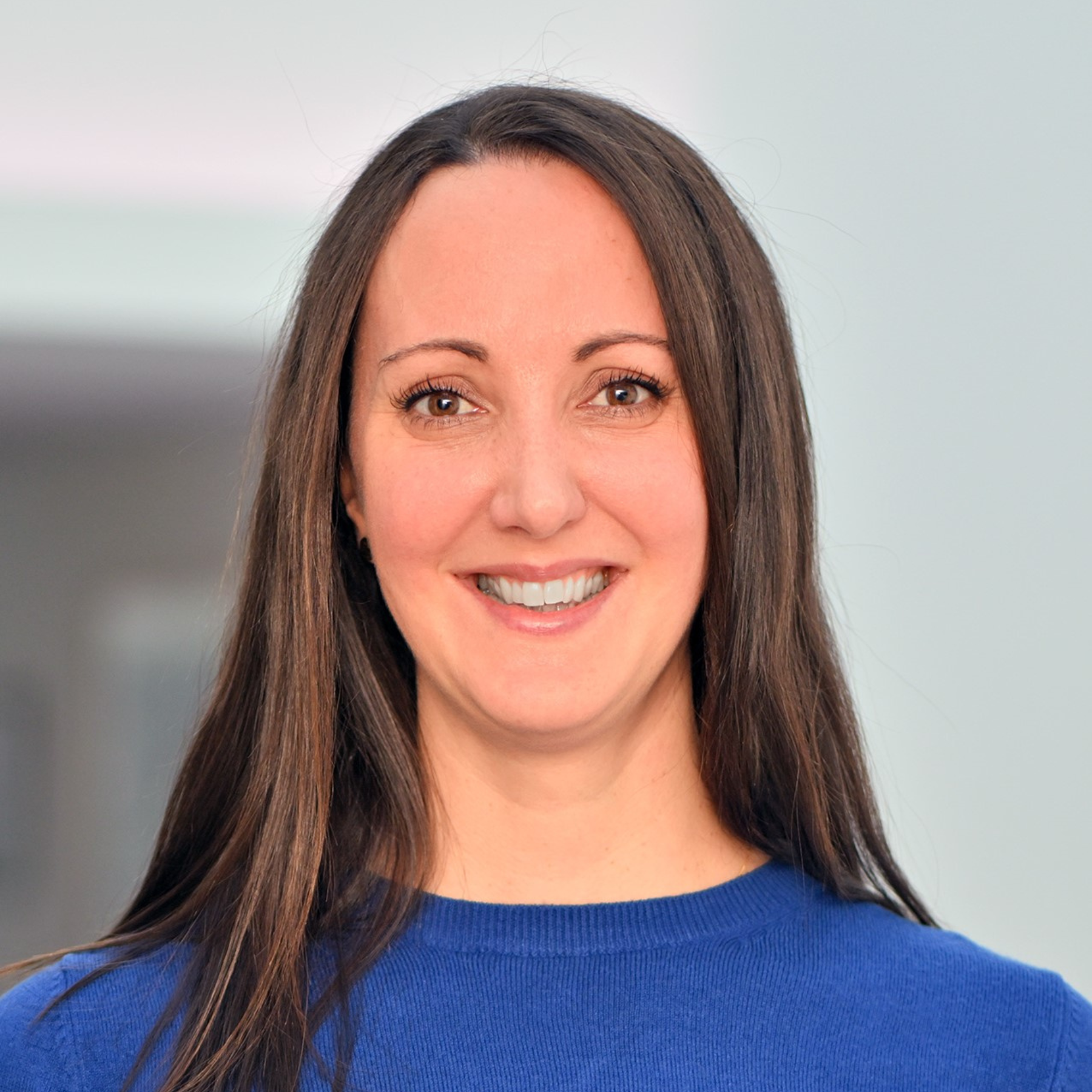 portait of woman smiling with long brown hair wearing a blue top