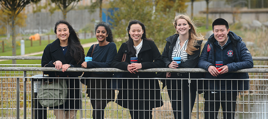 Medical students in social setting, standing by a railing.