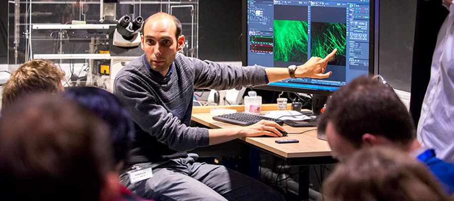 A genetic researcher pointing at data on a computer monitor