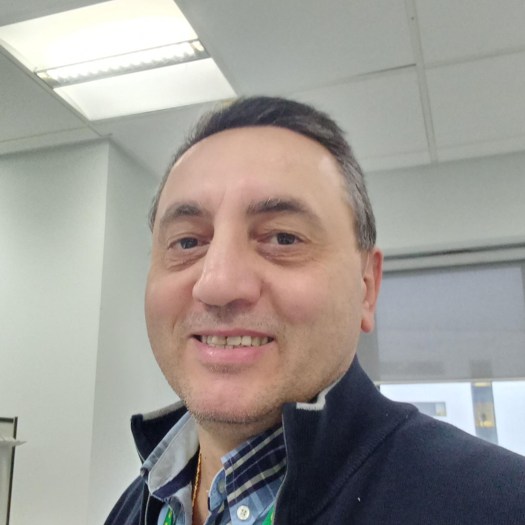 portrait of man smiling wearing navy jumper and check shirt