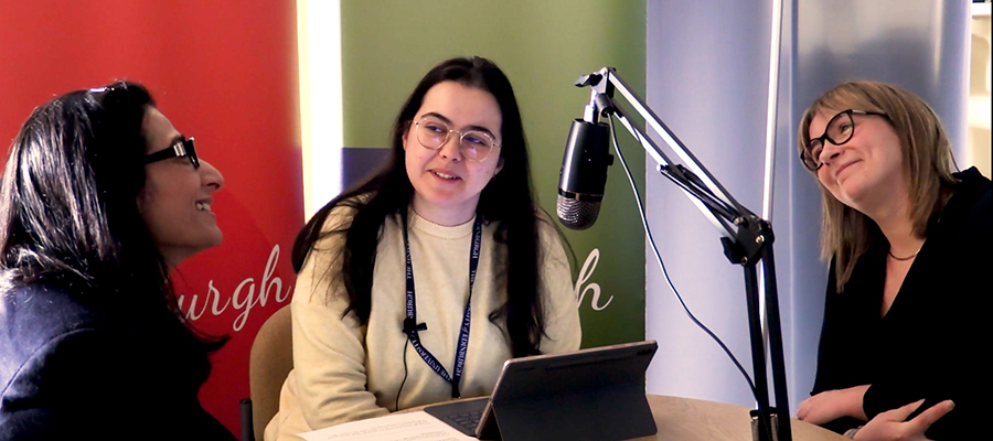 Three guests recording a podcast, with a microphone in the foreground